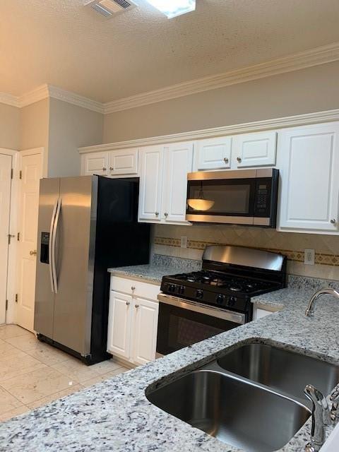 kitchen featuring stainless steel appliances, white cabinetry, and sink