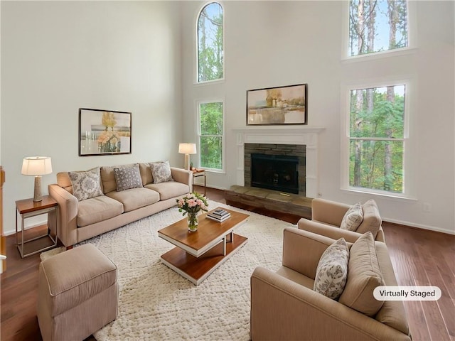 living room featuring a fireplace, wood-type flooring, and a high ceiling