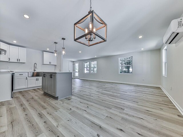 kitchen featuring white cabinets, decorative light fixtures, light hardwood / wood-style flooring, and sink