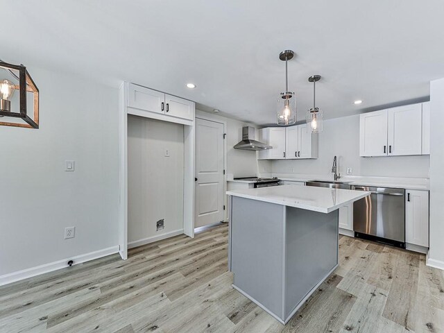 kitchen with white cabinetry, wall chimney range hood, sink, and appliances with stainless steel finishes