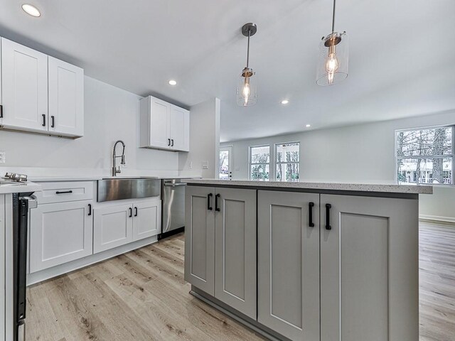 kitchen featuring dishwasher, white cabinets, sink, hanging light fixtures, and range