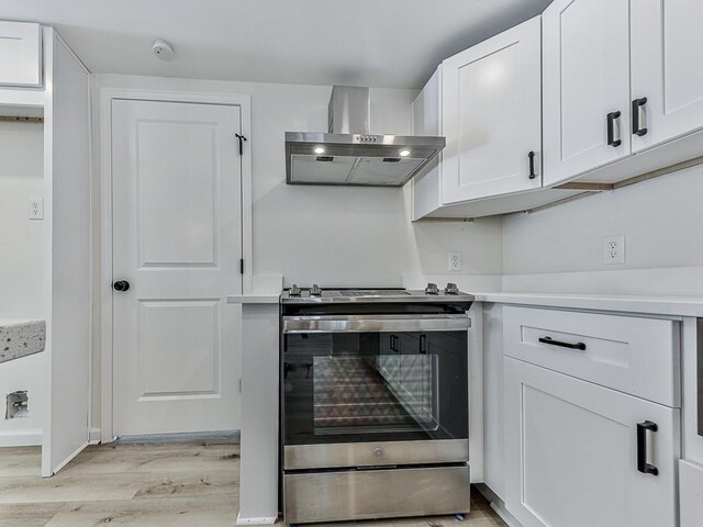 kitchen featuring light hardwood / wood-style floors, white cabinetry, stainless steel range oven, and wall chimney range hood