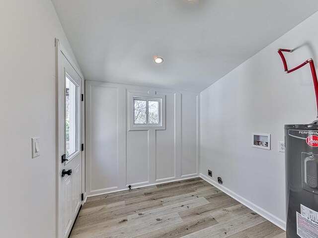 laundry room with hookup for a washing machine, electric water heater, and light hardwood / wood-style flooring