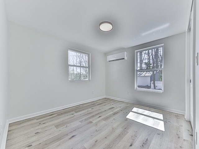 spare room featuring light wood-type flooring and an AC wall unit