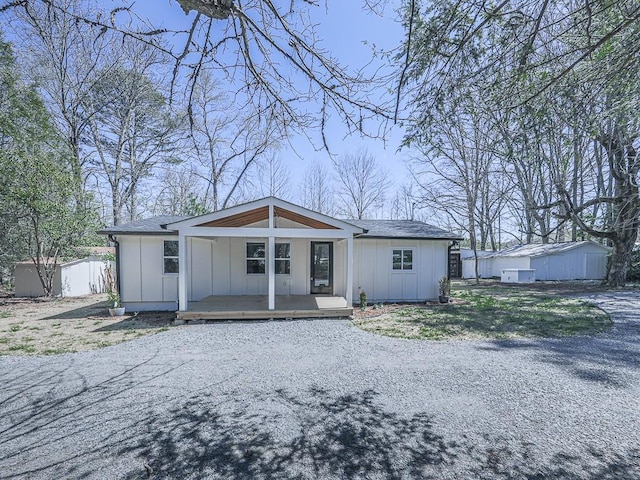 rear view of house with covered porch and a shed