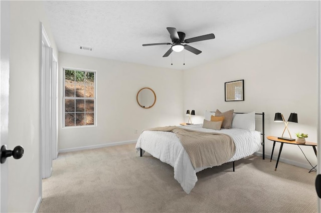 bedroom featuring ceiling fan, light carpet, and a textured ceiling