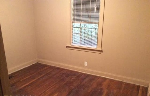 unfurnished room with baseboards and dark wood-style flooring