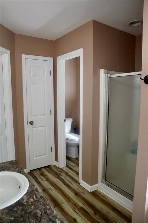 bathroom with hardwood / wood-style floors, vanity, toilet, and walk in shower