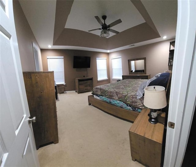 carpeted bedroom featuring ceiling fan, a raised ceiling, and a fireplace