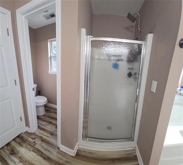 bathroom with wood-type flooring, a shower with shower door, and toilet