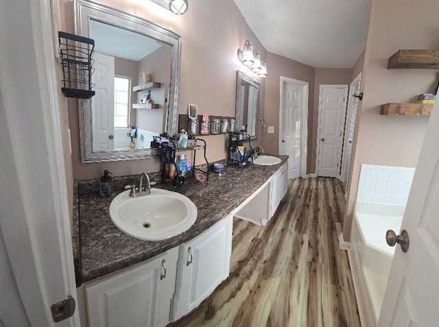 bathroom featuring hardwood / wood-style floors, vanity, and a tub to relax in