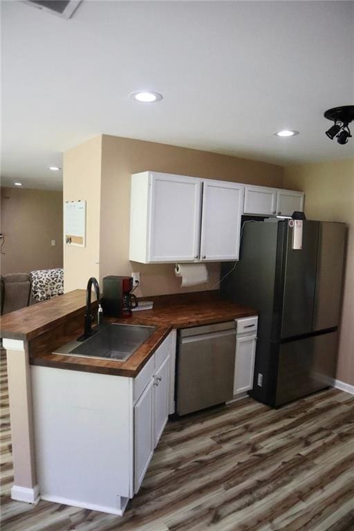 kitchen with white cabinets, black refrigerator, sink, stainless steel dishwasher, and kitchen peninsula