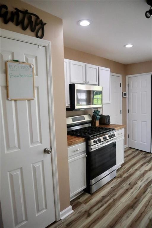 kitchen with wooden counters, appliances with stainless steel finishes, dark hardwood / wood-style flooring, and white cabinets