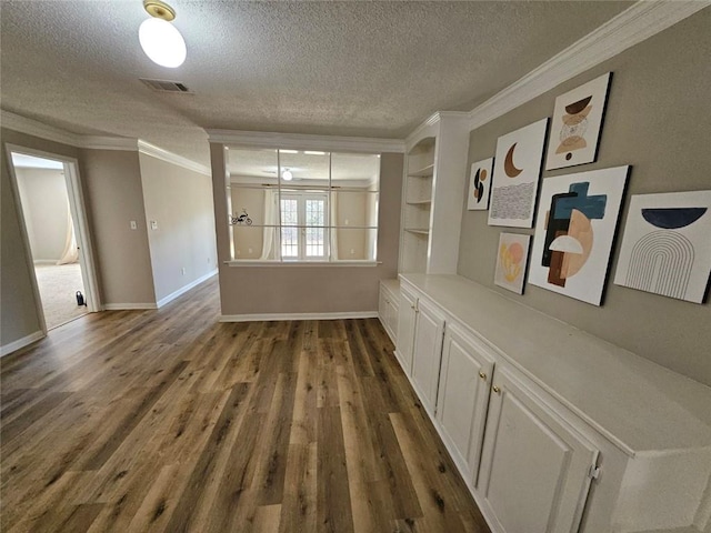 corridor featuring crown molding, dark wood-type flooring, and a textured ceiling