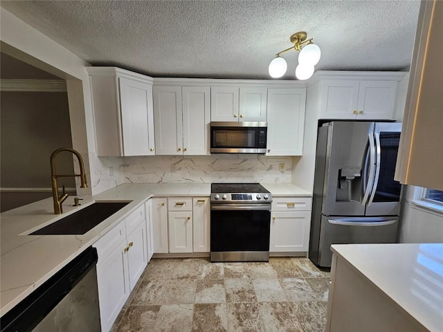 kitchen featuring sink, light stone counters, appliances with stainless steel finishes, white cabinets, and backsplash