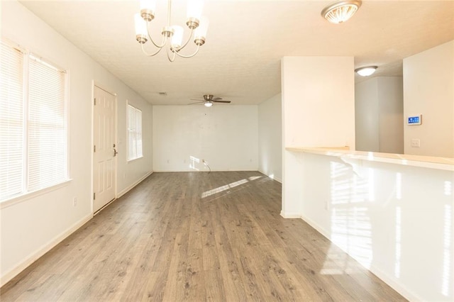 foyer featuring light wood-style flooring, baseboards, and ceiling fan with notable chandelier