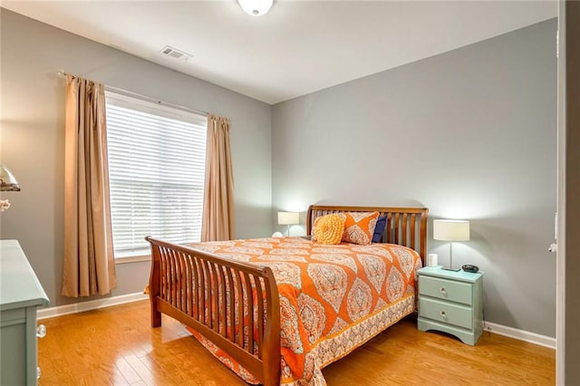 bedroom with multiple windows and hardwood / wood-style floors