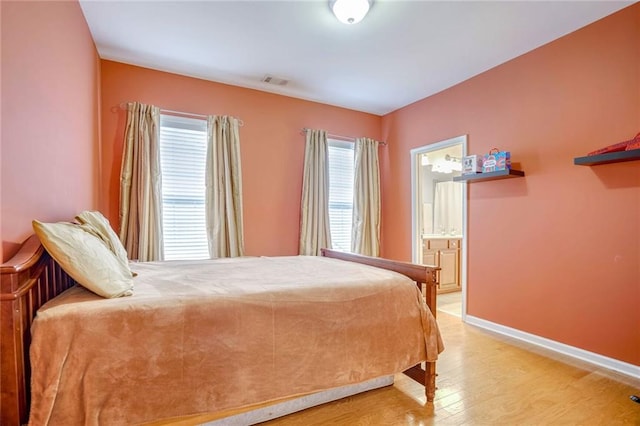 bedroom featuring wood-type flooring and ensuite bath