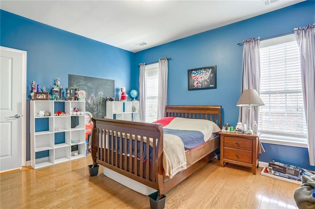 bedroom with light hardwood / wood-style floors and multiple windows