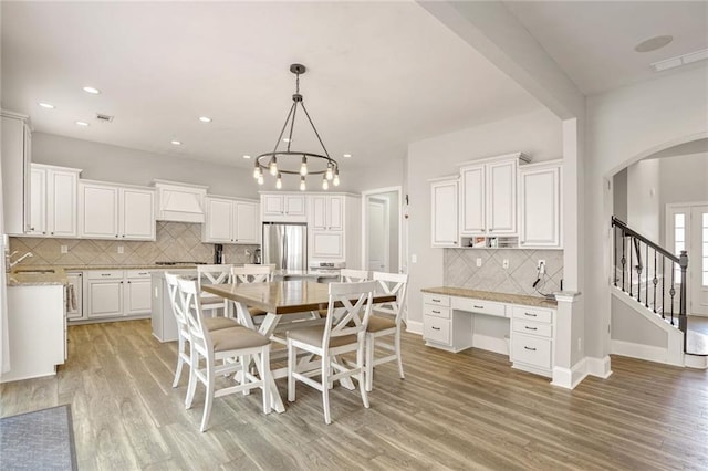 dining space with sink, light hardwood / wood-style flooring, and a notable chandelier