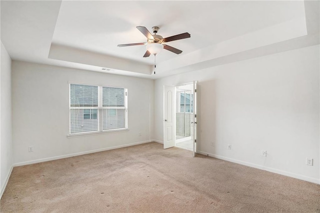 carpeted spare room featuring ceiling fan and a tray ceiling