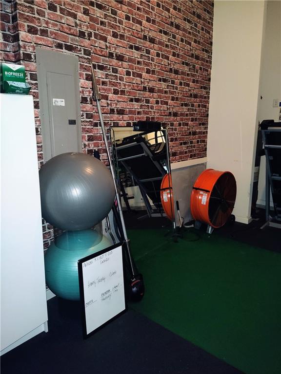 exercise area featuring electric panel and brick wall