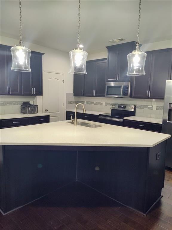 kitchen featuring appliances with stainless steel finishes, a center island with sink, dark hardwood / wood-style floors, and sink