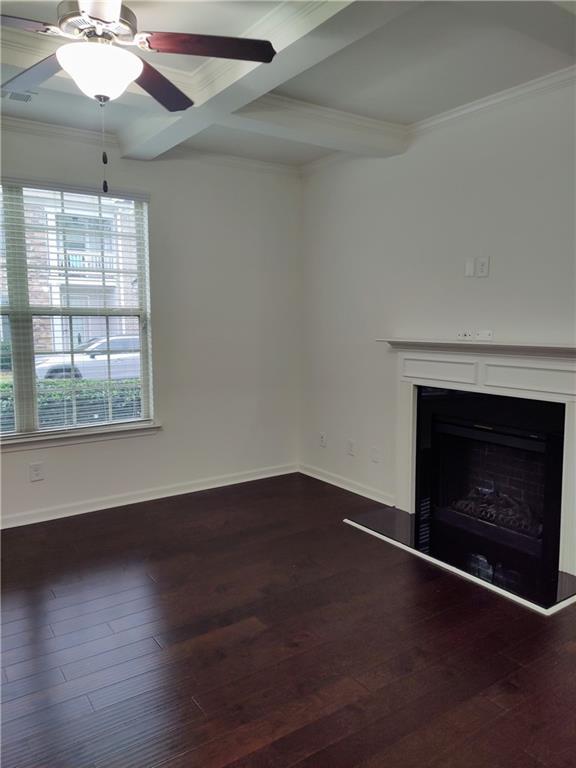 unfurnished living room with ceiling fan, beamed ceiling, dark wood-type flooring, and ornamental molding