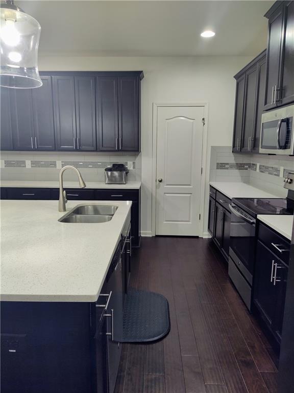 kitchen with decorative backsplash, stainless steel appliances, dark wood-type flooring, and sink