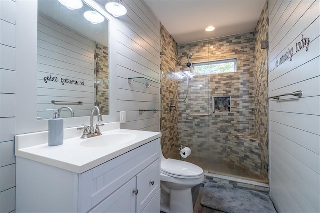 bathroom featuring toilet, wood walls, a shower stall, and vanity