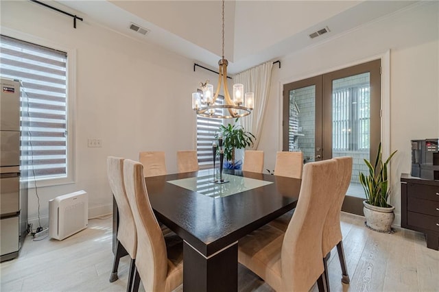 dining room with french doors, light hardwood / wood-style flooring, an inviting chandelier, and a wealth of natural light