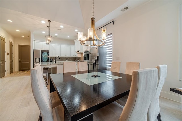 dining room with sink, vaulted ceiling, and an inviting chandelier