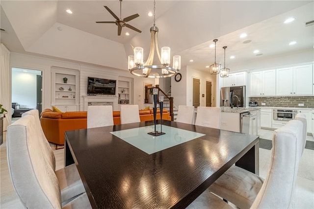 dining space with ceiling fan with notable chandelier, a raised ceiling, sink, vaulted ceiling, and built in shelves