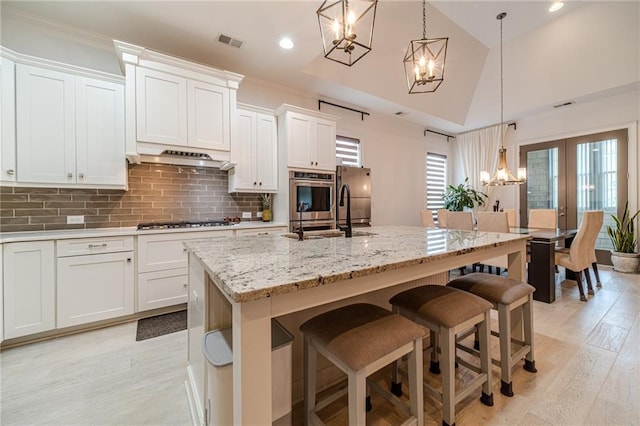 kitchen featuring white cabinetry, a kitchen island with sink, and hanging light fixtures