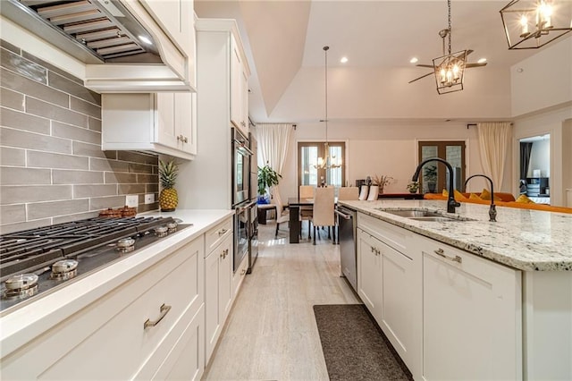 kitchen with lofted ceiling, white cabinets, decorative light fixtures, and custom range hood