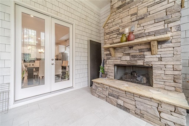 living room featuring french doors, an outdoor stone fireplace, and ornamental molding