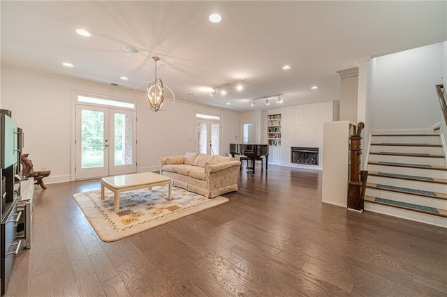 living room featuring french doors, track lighting, ornamental molding, dark wood-type flooring, and a fireplace