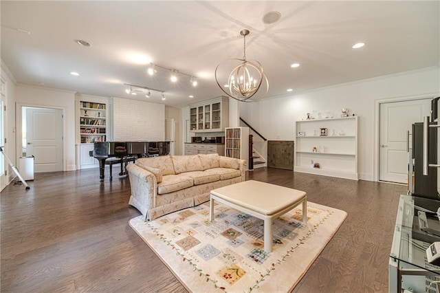 living room featuring built in shelves, crown molding, dark hardwood / wood-style flooring, and an inviting chandelier