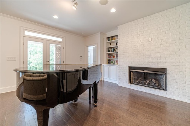 miscellaneous room with french doors, dark wood-type flooring, a brick fireplace, built in features, and crown molding