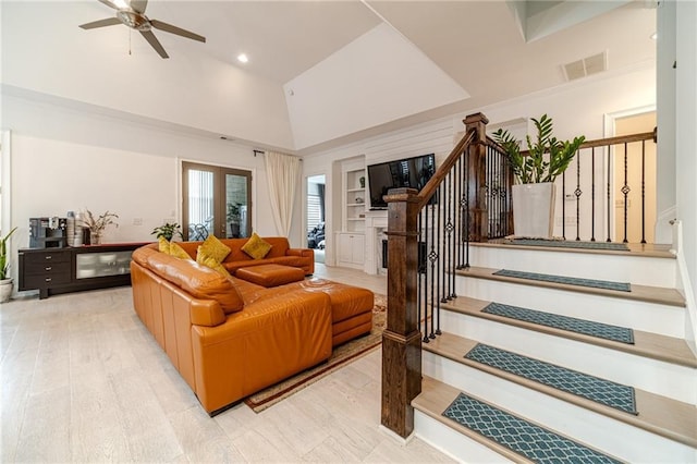 living room with ceiling fan, light hardwood / wood-style flooring, and a towering ceiling