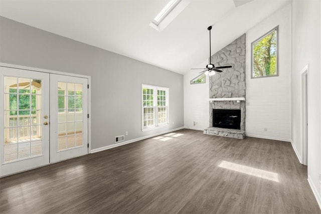 unfurnished living room with visible vents, dark wood-type flooring, ceiling fan, a stone fireplace, and high vaulted ceiling