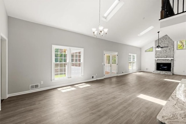 unfurnished living room with visible vents, high vaulted ceiling, ceiling fan with notable chandelier, wood finished floors, and a fireplace