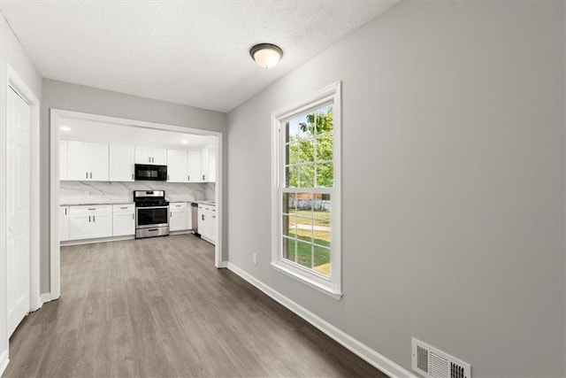 kitchen with visible vents, light countertops, black microwave, white cabinetry, and gas range