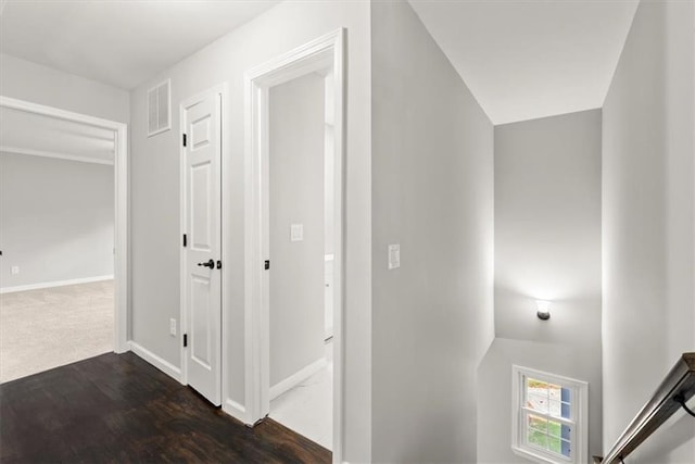 hallway featuring visible vents, dark wood-type flooring, and baseboards