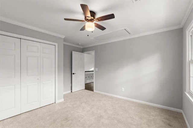 unfurnished bedroom with carpet, baseboards, attic access, ornamental molding, and a closet