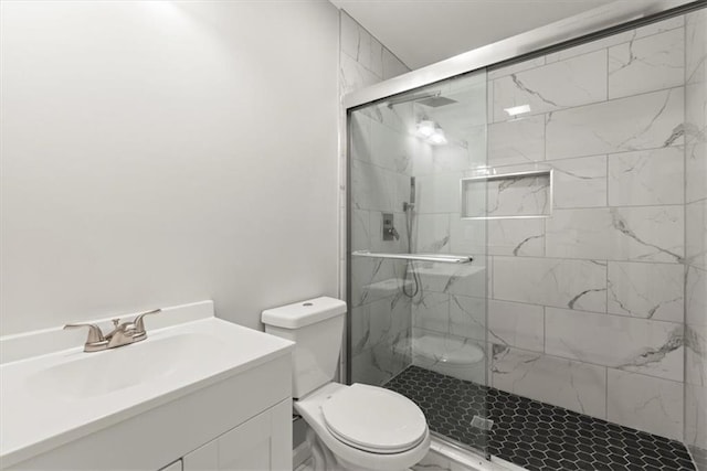 bathroom featuring toilet, a stall shower, and vanity