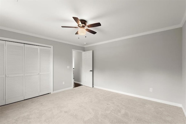 unfurnished bedroom with a closet, crown molding, baseboards, and carpet floors