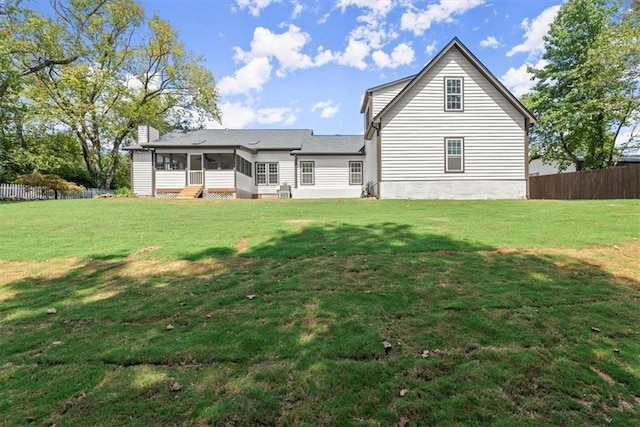 rear view of house featuring fence, a yard, and a sunroom