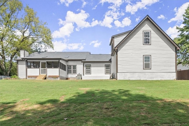 rear view of house with a lawn and a sunroom