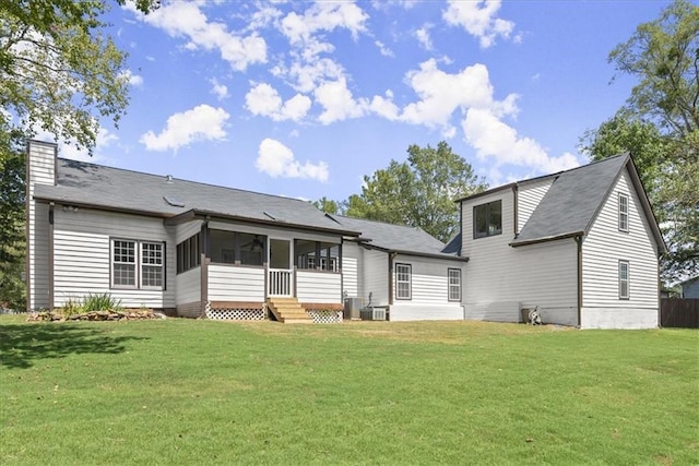 rear view of property featuring a yard, central AC unit, a chimney, and a sunroom